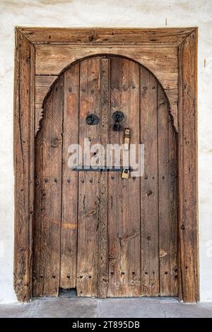 Vecchia porta in legno ad arco con serratura in ferro e bullone. Monastero della Santa Croce a Omodos. Cipro. Foto Stock