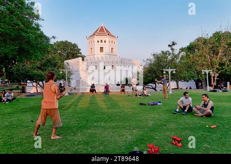 Turisti stranieri che si rilassano nel Parco Santichaiprakarn a Banglamphu, (Banglamphoo), Bangkok, Thailandia, il vecchio forte di Phra Sumen sullo sfondo Foto Stock