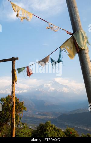 Bandiere di preghiera tibetane pendono su una vista di Machhapuchhare e della valle del fiume Seti, Nepal Foto Stock