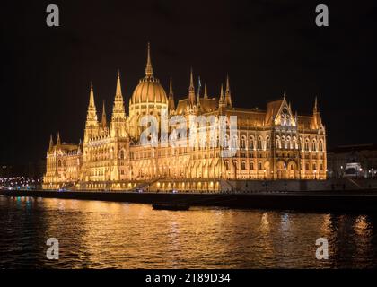 L'iconico ma grande Parlamento ungherese illuminato di notte non appena dal Danubio Foto Stock