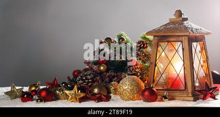 Composizione di Natale della lanterna ornamenti colorati sfere stelle candele e Abete rami sulla neve Foto Stock