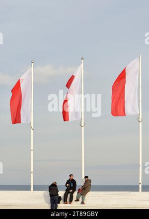 Bandiere nazionali polacche e turisti asiatici al molo di Sopot fuori stagione in una fredda e soleggiata giornata invernale a Sopot, Pomerania, Polonia, Europa, UE Foto Stock