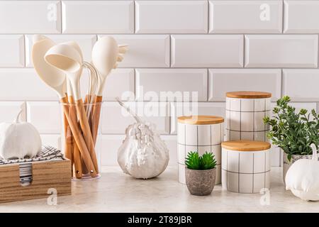 Cucina moderna con elementi di arredo naturale e zucche bianche. Vasetti eleganti per riporre i tuoi oggetti. Asciugamano in una scatola di legno. Foto Stock