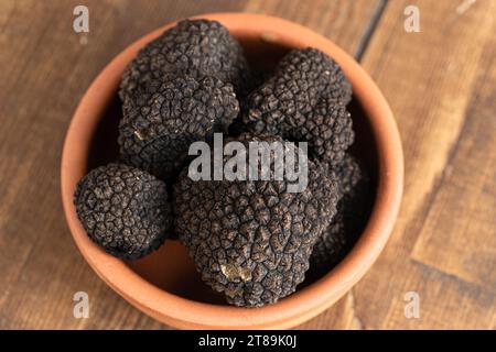Tartufo nero in un vaso di argilla su fondo di legno. Primo piano. Foto Stock