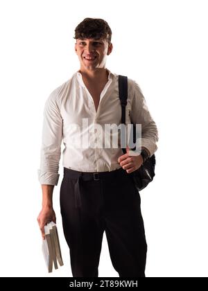 Un giovane uomo attraente con una camicia bianca e pantaloni neri, uno studente sorridente con zaino e libri in una mano Foto Stock
