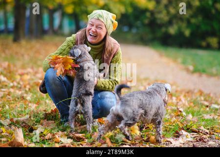 Donna felice con il cane nel parco autunnale. Donna sorridente con animale domestico. Foto Stock