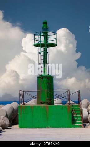 Faro verde in metallo arrugginito su piattaforma in cemento sulla Costa di Fiumicino, Provincia di Roma, Italia Foto Stock