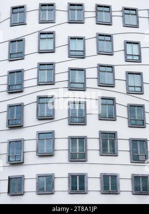 Foto verticale architettonica minimalista di Dacing House a Praga, Cechia. Molte finestre nell'edificio moderno beige dal design unico Foto Stock