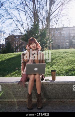 Giovane adulto asiatico donna lavoro con computer portatile all'aperto Foto Stock