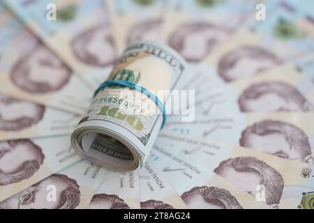 Un sacco di centinaia di banconote da dollari americani si trova su molte banconote di hryvna ucraine. Default economico, crisi e svalutazione del curren nazionale ucraino Foto Stock