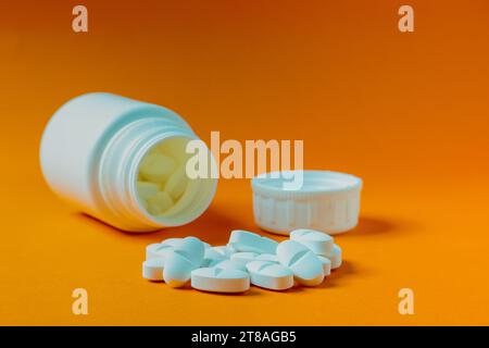 Primo piano di un gruppo di compresse bianche con un flacone di prescrizione fuori fuoco sullo sfondo. Foto Stock