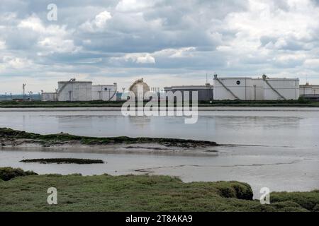 Vista del fiume dall'isola di Canvey attraverso Holehaven Creek verso il sito della raffineria petrolifera di Coryton (ora chiuso). Contenitori di stoccaggio dell'olio. Essex, Inghilterra, Regno Unito 2023. Foto Stock