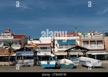 Villaggio di pescatori di Pedregalejo, Malaga: Le barche da pesca si trovano sulla sabbia di fronte al lungomare con i suoi chiringuitos e bancarelle di barbecue a base di pesce Foto Stock