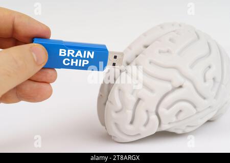 Un uomo inserisce una chiavetta nel suo cervello con l'iscrizione - chip cerebrale. Concetto aziendale e tecnologico. Foto Stock