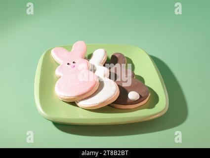 I migliori dolci di Pasqua: Tre adorabili biscotti di coniglio su un piatto verde pastello Foto Stock