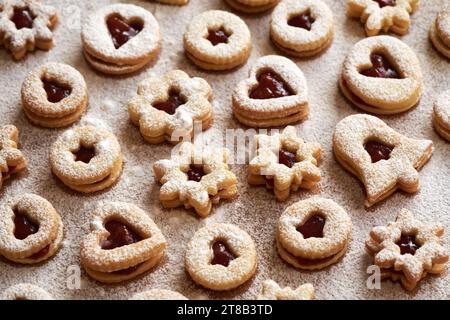 Biscotti natalizi Linzer fatti in casa ripieni di marmellata e spolverati con zucchero su un tavolo Foto Stock