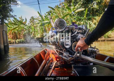 Potente motore della tradizionale barca a coda lunga in Thailandia. La barca di controllo della guida nello stretto canale d'acqua che conduce al mercato galleggiante Damnoen Saduak. Foto Stock