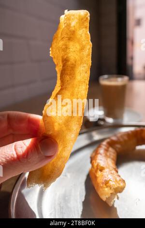 Churros appena sfornati con un bicchiere di caffè e latte Foto Stock