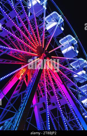 Ruota panoramica, conosciuta anche come gigantesca ruota panoramica, popolare giro divertente nel parco divertimenti, scena notturna vista dall'angolo basso con messa a fuoco selettiva Foto Stock