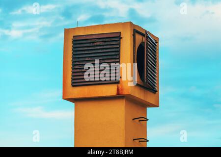 Uscita camino di ventilazione con griglia arrugginita contro cielo blu Foto Stock