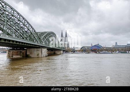 Rhein Hochwasser in Köln beim Pegel von 693 cm aus Sicht des Deutzer Rheinufers auf die Innenstadt von Köln. mit Kölner Dom, Musical Dome und Hohenzollernbrücke. Warnschilder in deutscher und englischer Sprache wurden aufgestellt und erste Abschnitte abgesperrt. Es wird derzeit mit einem steigenden Pegel von über 7 Metern gerechnet. 19.11.2023 Köln Deutz NRW Deutschland *** le inondazioni del Reno a Colonia ad un livello di 693 cm dalla riva Deutz del Reno come visto dal centro della città di Colonia con la cattedrale di Colonia, la cupola musicale e il ponte Hohenzollern sono stati messi cartelli di avvertimento in tedesco e inglese Foto Stock