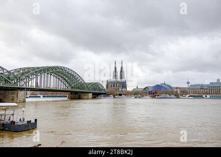 Rhein Hochwasser in Köln beim Pegel von 693 cm aus Sicht des Deutzer Rheinufers auf die Innenstadt von Köln. mit Kölner Dom, Musical Dome und Hohenzollernbrücke. Warnschilder in deutscher und englischer Sprache wurden aufgestellt und erste Abschnitte abgesperrt. Es wird derzeit mit einem steigenden Pegel von über 7 Metern gerechnet. 19.11.2023 Köln Deutz NRW Deutschland *** le inondazioni del Reno a Colonia ad un livello di 693 cm dalla riva Deutz del Reno come visto dal centro della città di Colonia con la cattedrale di Colonia, la cupola musicale e il ponte Hohenzollern sono stati messi cartelli di avvertimento in tedesco e inglese Foto Stock