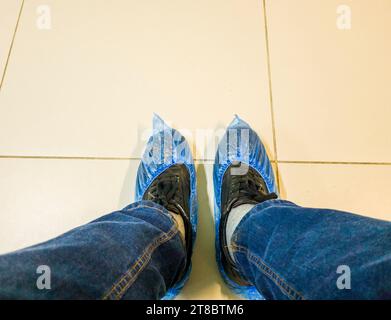 Persona nei jeans che indossa copriscarpe in clinica Foto Stock