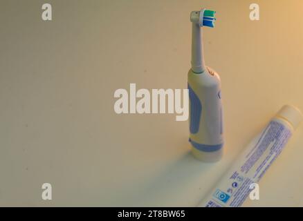 Una foto di un alto spazzolino elettrico bianco accanto a un tubo schiacciato di dentifricio. Foto Stock
