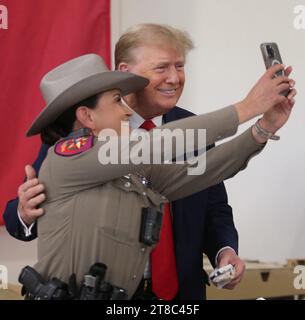 Edinburg, Texas USA, 19 novembre 2023: L'ex presidente DONALD TRUMP, un candidato per la nomina presidenziale repubblicana, posa per una foto con un membro femminile del Dipartimento di pubblica sicurezza del Texas presso l'Aeroporto Internazionale del Texas meridionale. Trump è volato per una manifestazione elettorale all'aeroporto. Foto di Michael Gonzalez/Pool Foto Stock