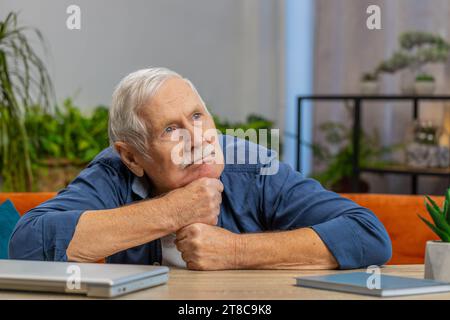 Ritratto di triste e stressato vecchio nonno seduto a casa sembra pensivo pensa alle preoccupazioni di vita, soffre di situazione ingiusta. Problema crisi depressione sentirsi male male male male infastidito bruciato Foto Stock