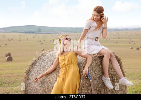 Belle donne hippie felici con la chitarra in campo Foto Stock