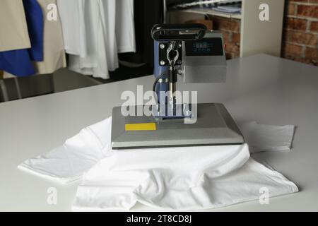 Stampa logo. Pressa a caldo con t-shirt su tavolo bianco Foto Stock