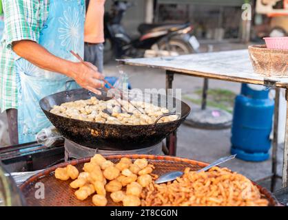 L'uomo che frigge l'impasto fritto in padella con olio da cucina caldo. Il cibo di strada in Thailandia. Foto Stock