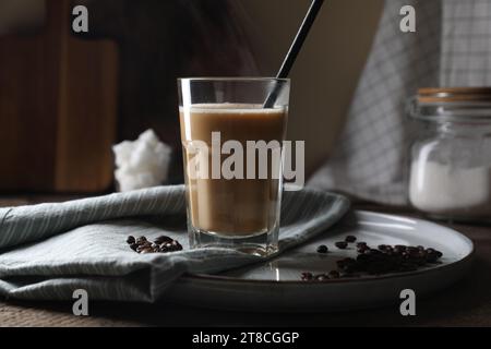 Bevanda a base di caffè in vetro con paglia e chicchi su un tavolo di legno Foto Stock