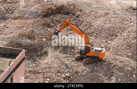 Il grande escavatore cingolato con martello idraulico rompe l'asfalto in un cantiere Foto Stock