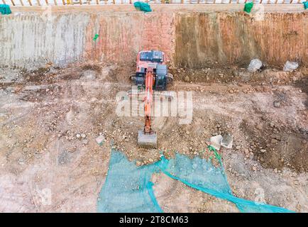 Il grande escavatore cingolato con martello idraulico rompe l'asfalto in un cantiere Foto Stock