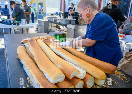 NEW ORLEANS, LOS ANGELES, USA - 19 NOVEMBRE 2023: Donna che affetta pane francese per preparare panini da poboy al Poboy Festival 2023 di New Orleans Foto Stock