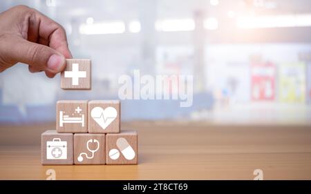 Assicurazione sanitaria e concetto di assistenza sanitaria, mano umana tiene blocco di legno con icone sull'assicurazione sanitaria e l'accesso alla sanità, pianificazione pensionistica su Foto Stock