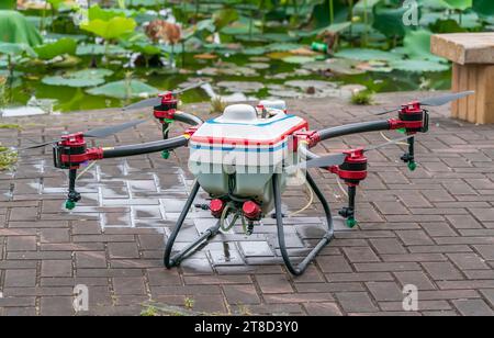 il drone agricolo trasporta un serbatoio di fertilizzante liquido che vola nel cielo blu preparatevi a spruzzarlo nell'area agricola Foto Stock