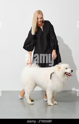 Felice donna bionda con il soffice cane samoyed Foto Stock