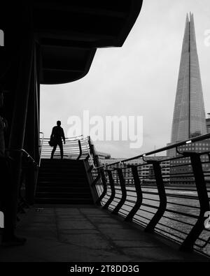 Immagine in bianco e nero della silhouette dell'uomo in cima ai gradini esterni con l'icona di Londra, The Shard sullo sfondo. Foto Stock