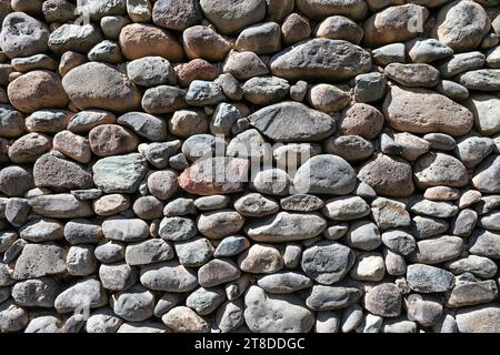 Robusto muro rustico costruito con pietre diverse. Sfondo della trama della parete in pietra Foto Stock