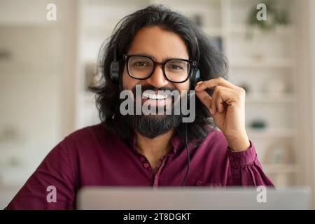 Operatore Call Center. Primo piano - Ritratto di Happy Young Indian Man in cuffia Foto Stock