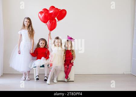 bellissimi bambini con palle rosse sedute sulle sedie Foto Stock