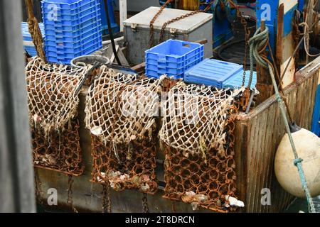 Barche rosse arrugginite e reti metalliche per la cattura delle capesante Foto Stock