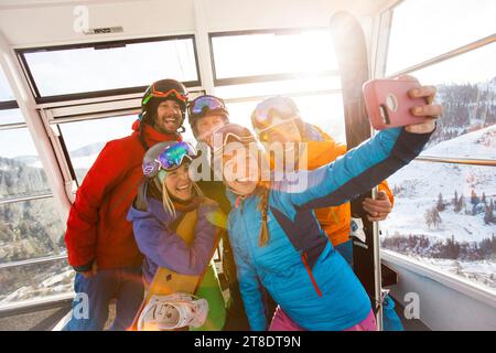 Gruppo di amici che scattano un selfie in gondola in una stazione sciistica. Foto Stock