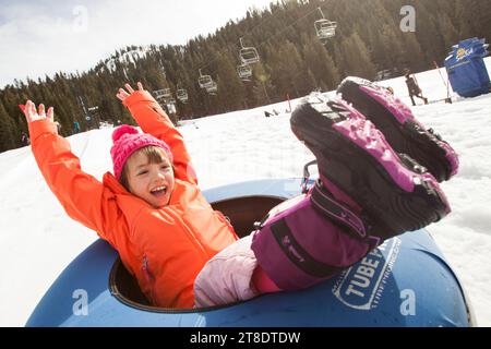 Giovane ragazza che fa tubing sulla neve e si diverte. Foto Stock