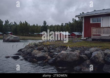 Case di legno rosse sulla riva del mare in un villaggio finlandese Foto Stock