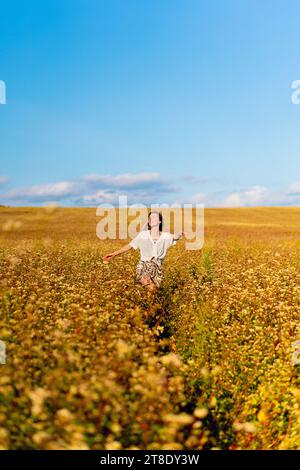 Giovane donna in un campo giallo estivo al tramonto. Foto Stock