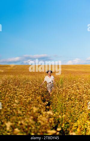 Giovane donna in un campo giallo estivo al tramonto. Foto Stock